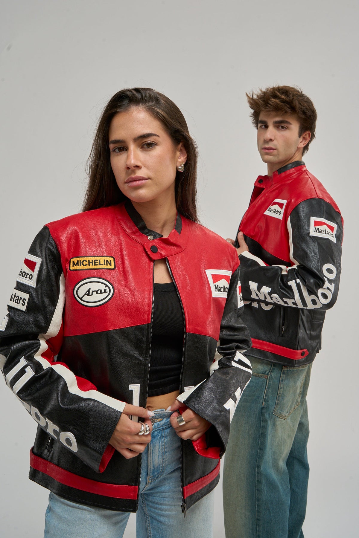 Man and woman wearing red and black vintage leather racing jackets with sponsor patches
