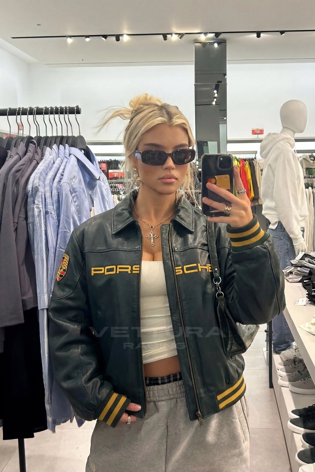 Close view of the gold Porsche wordmark on the green leather jacket