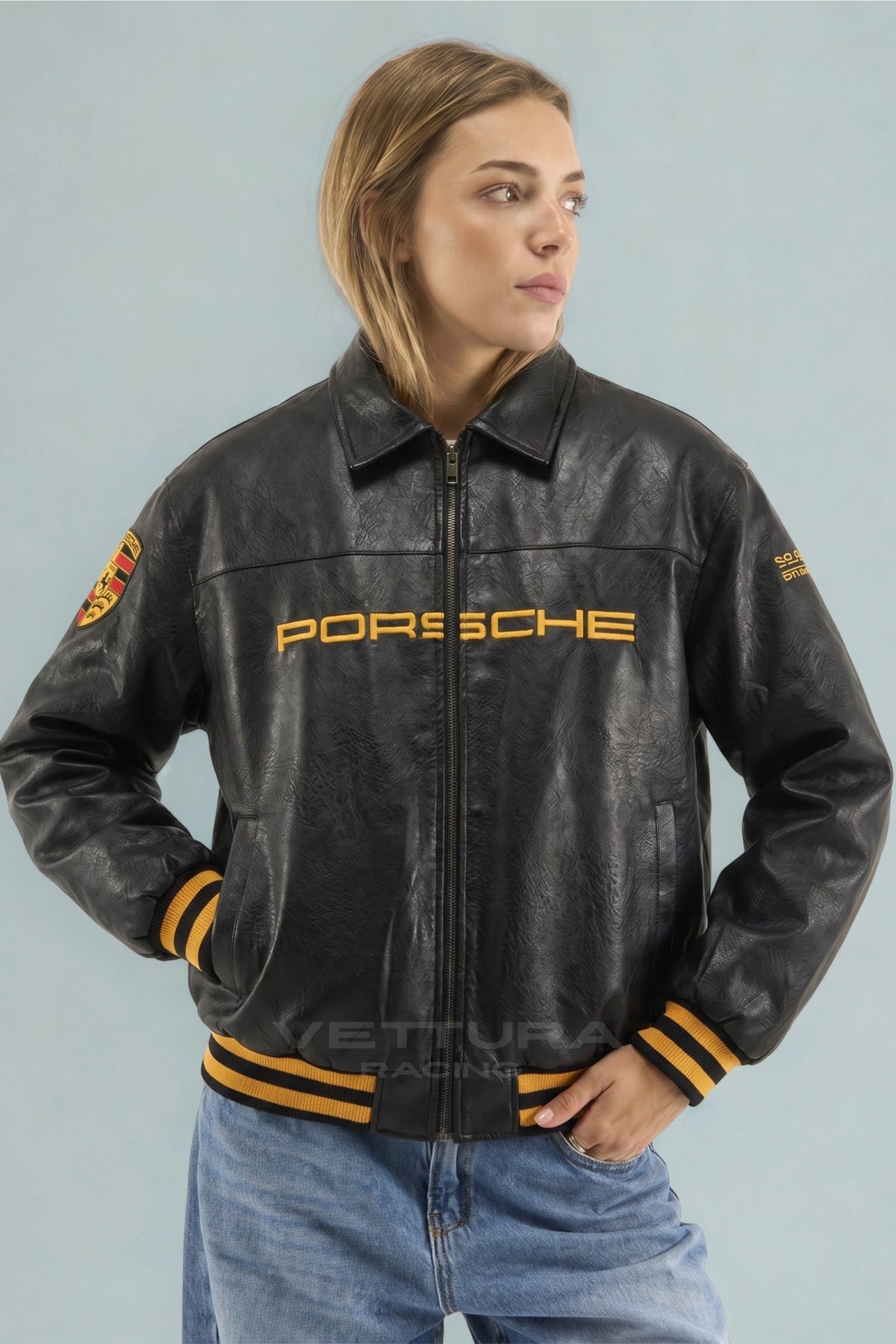 Close view of the gold Porsche wordmark on the black leather jacket