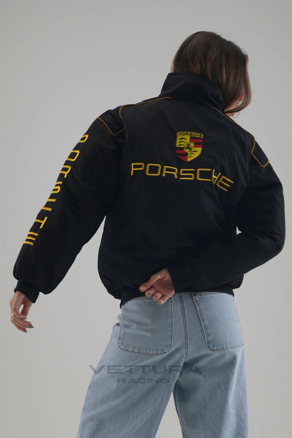 Rear view of the Porsche vintage racing jacket worn with wide leg jeans