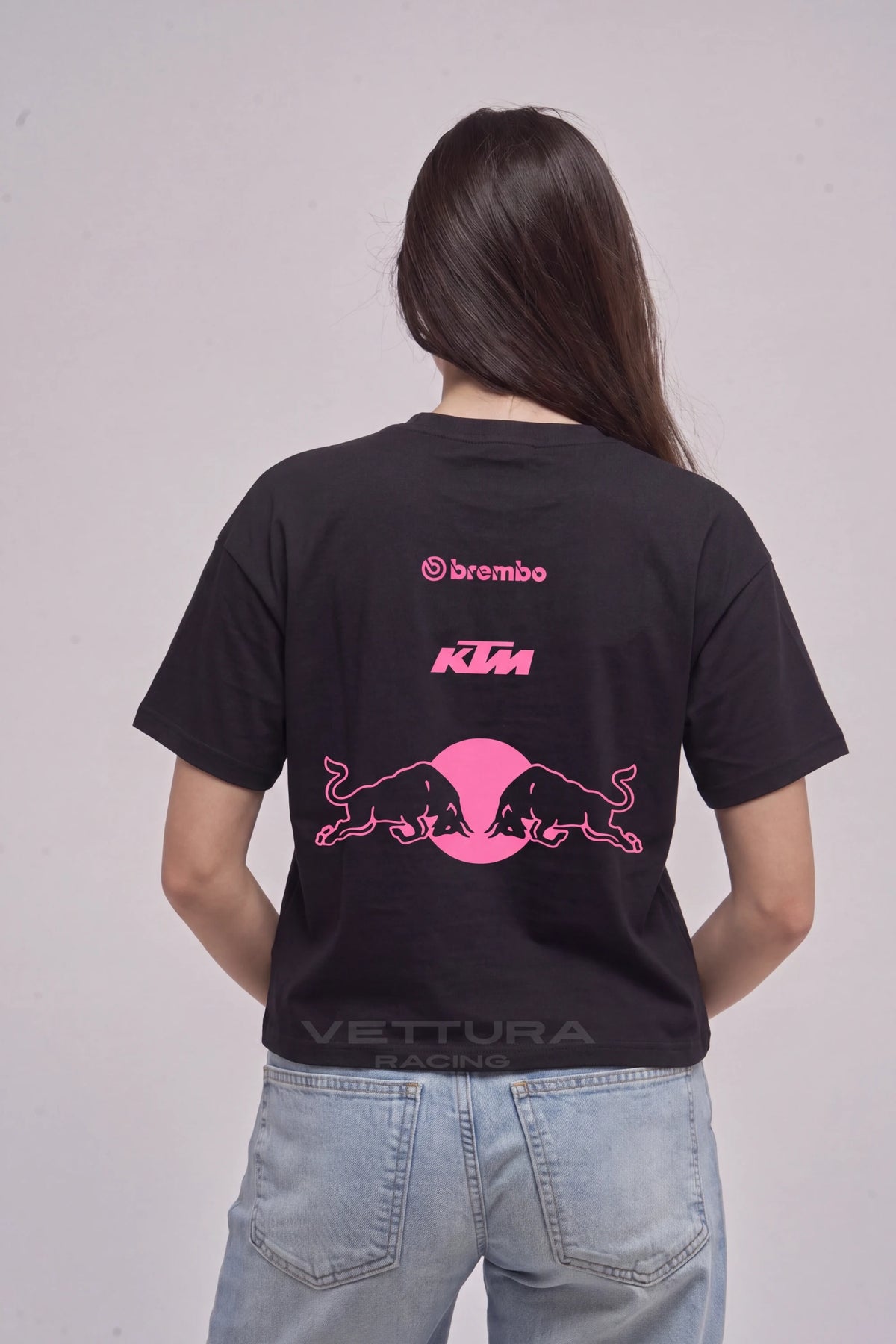 Woman wearing the Red Bull pink edition tee, back view with the pink bulls and KTM print