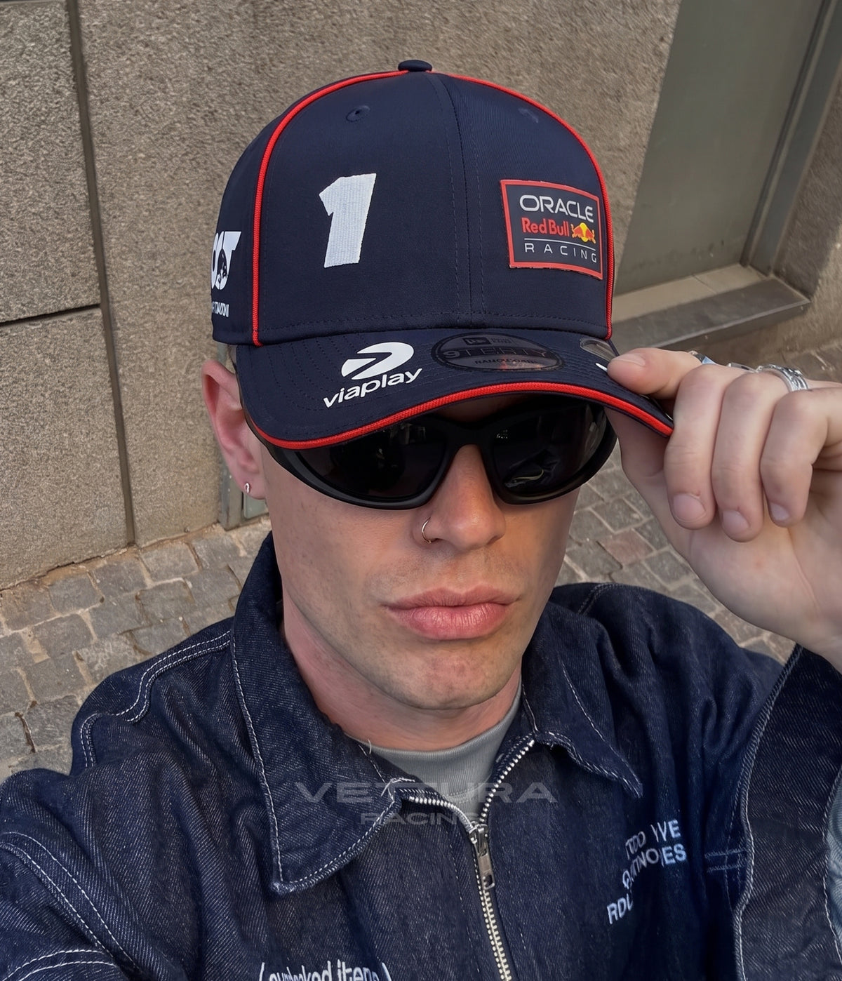 Man in a denim jacket wearing the navy Red Bull Racing 2023 cap with the No.1