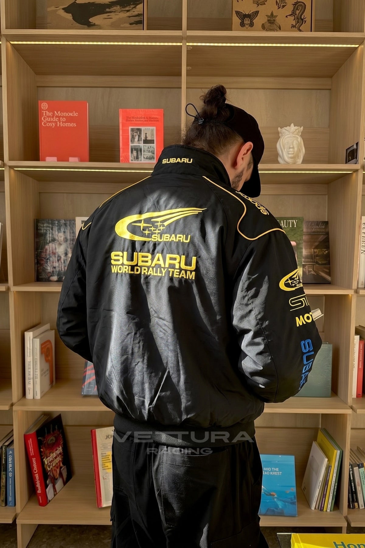 Indoor lifestyle shot of the black Subaru rally vintage racing jacket