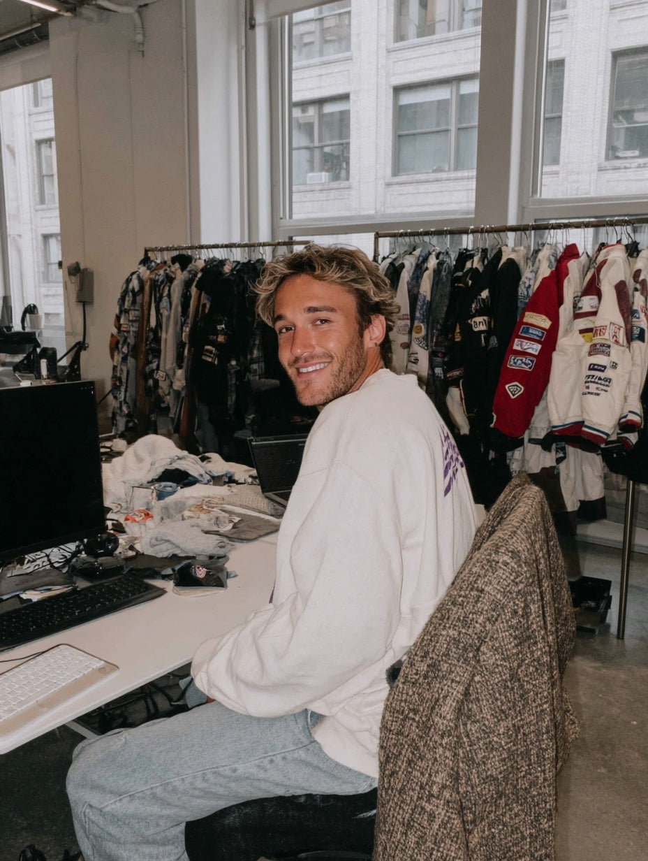 Smiling Vettura Racing team member in the studio in front of rails of vintage motorsport jackets