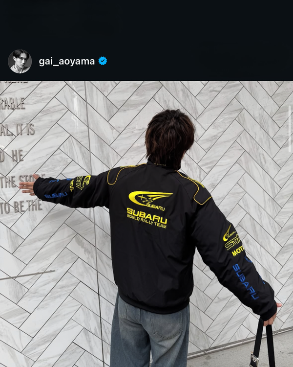 Back view of a man in a black Subaru World Rally Team vintage racing jacket