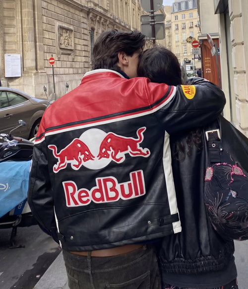Couple embracing, back view of a red and black Red Bull vintage leather racing jacket