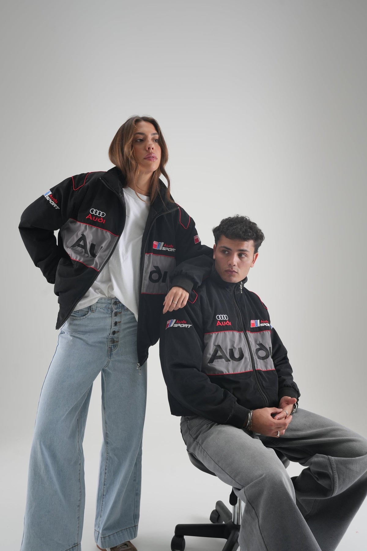 Man and woman wearing black Audi vintage racing jackets in the studio