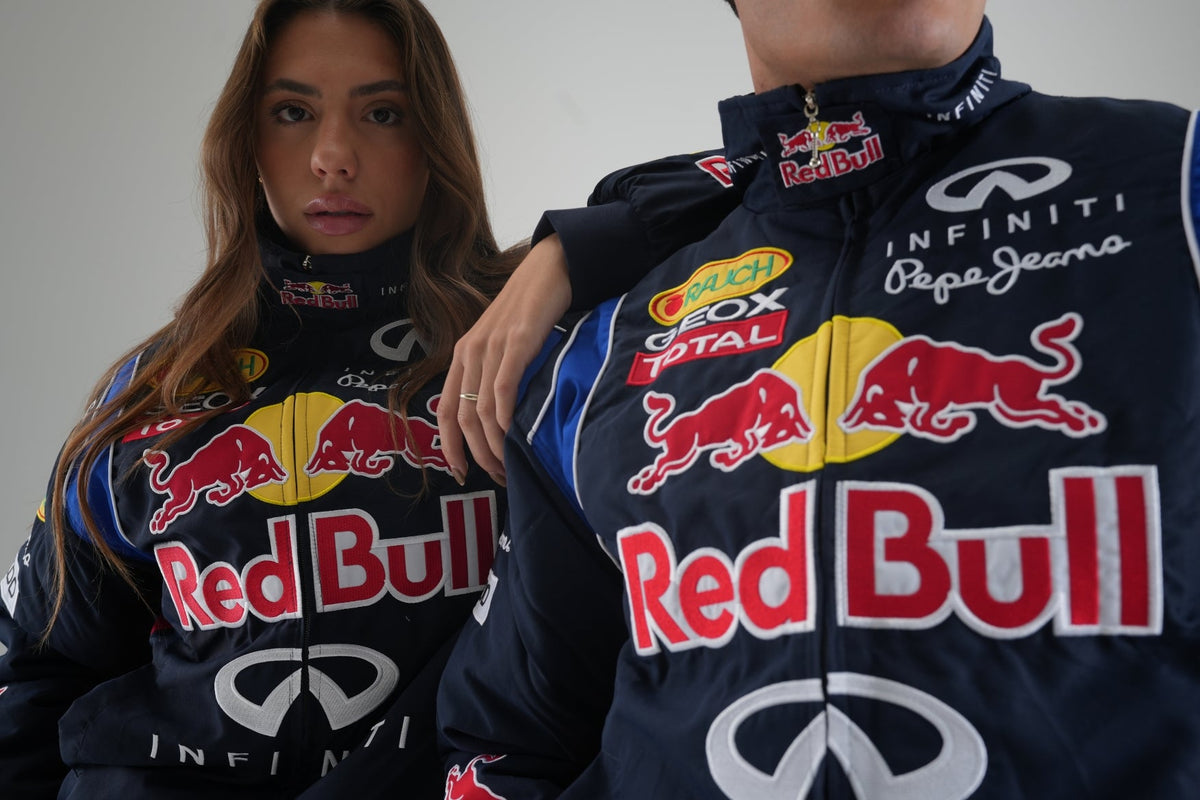 Man and woman wearing navy Red Bull F1 vintage racing jackets