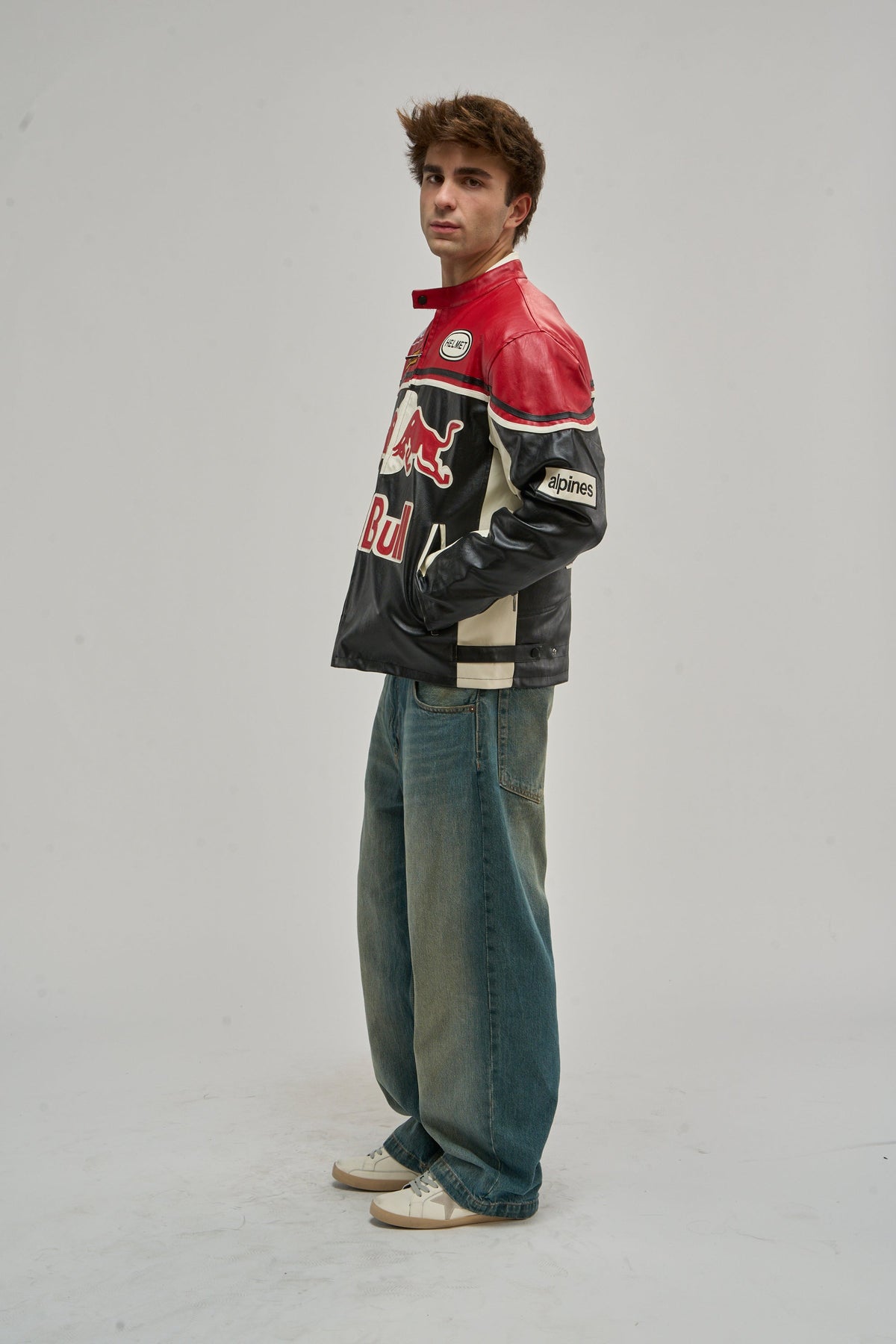 Man in a red, black and white vintage leather racing jacket, side view in the studio