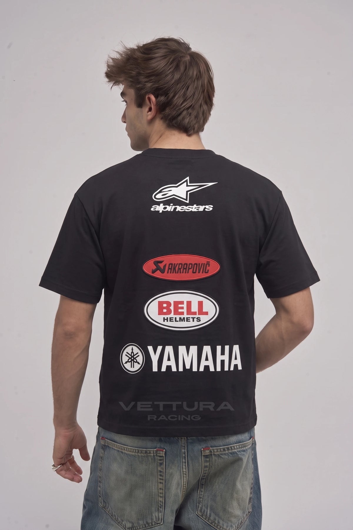 Man wearing the Alpinestars racing tee, back view with the Akrapovic, Bell and Yamaha panel