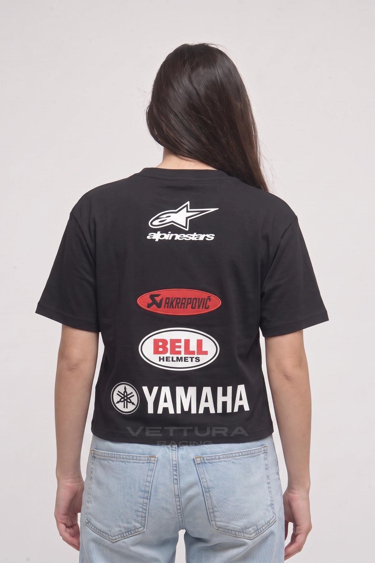 Woman wearing the Alpinestars racing tee, back view with the Akrapovic, Bell and Yamaha sponsor blocks