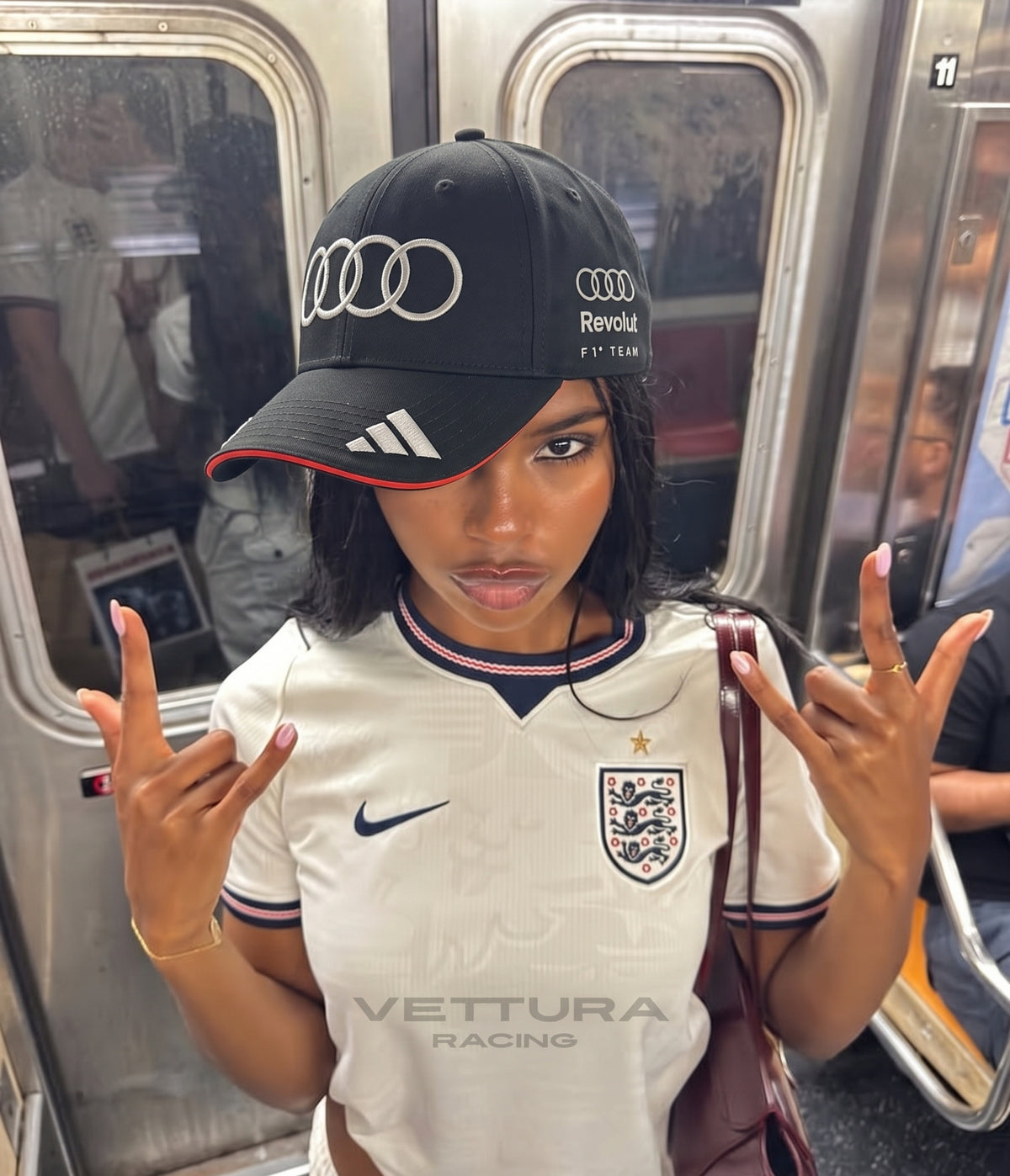 Woman wearing the black Audi F1 Team 2026 cap on a subway train