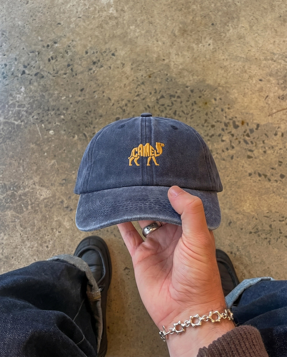 Blue Camel embroidered cap held in hand