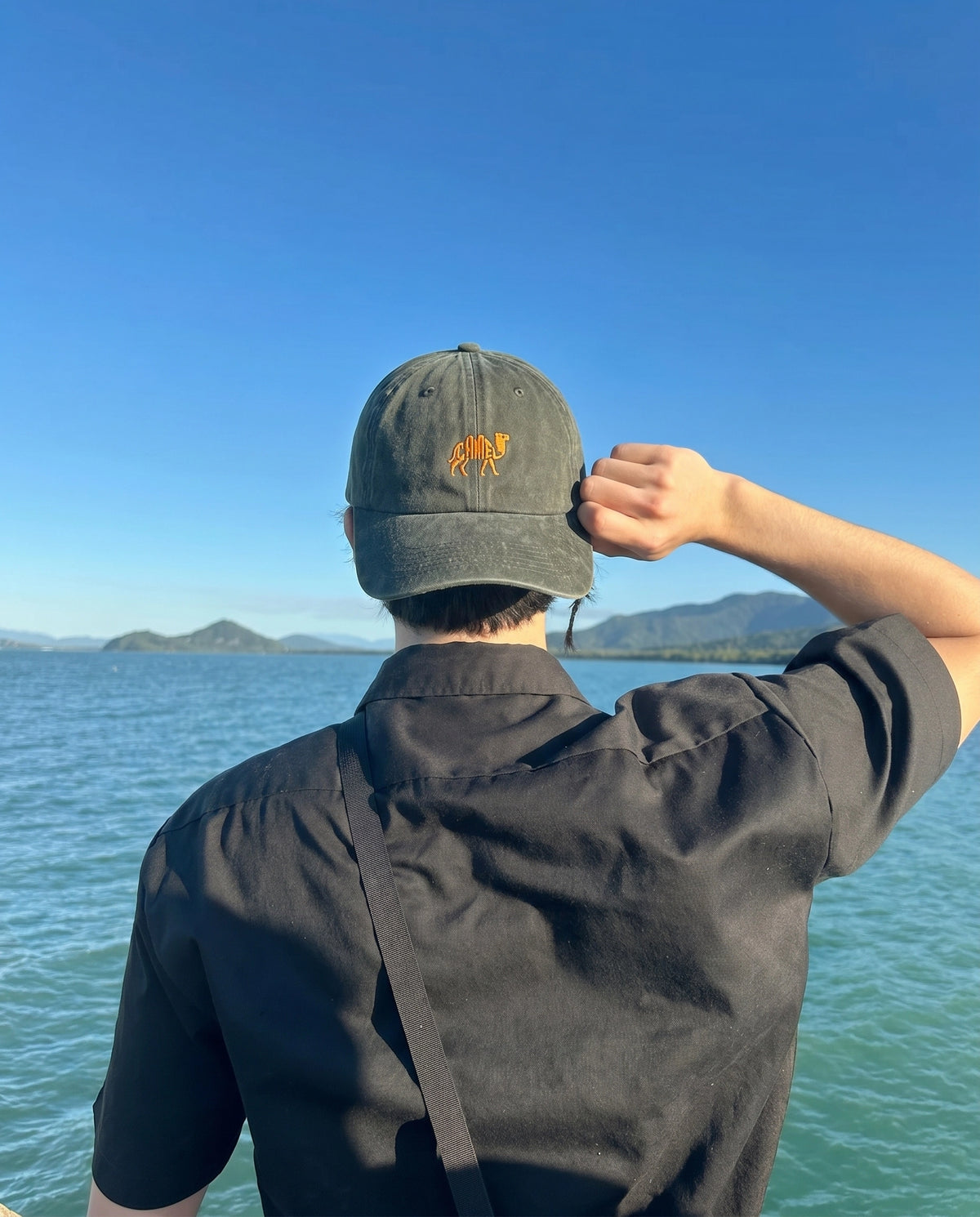 Camel embroidered cap worn against a blue sky