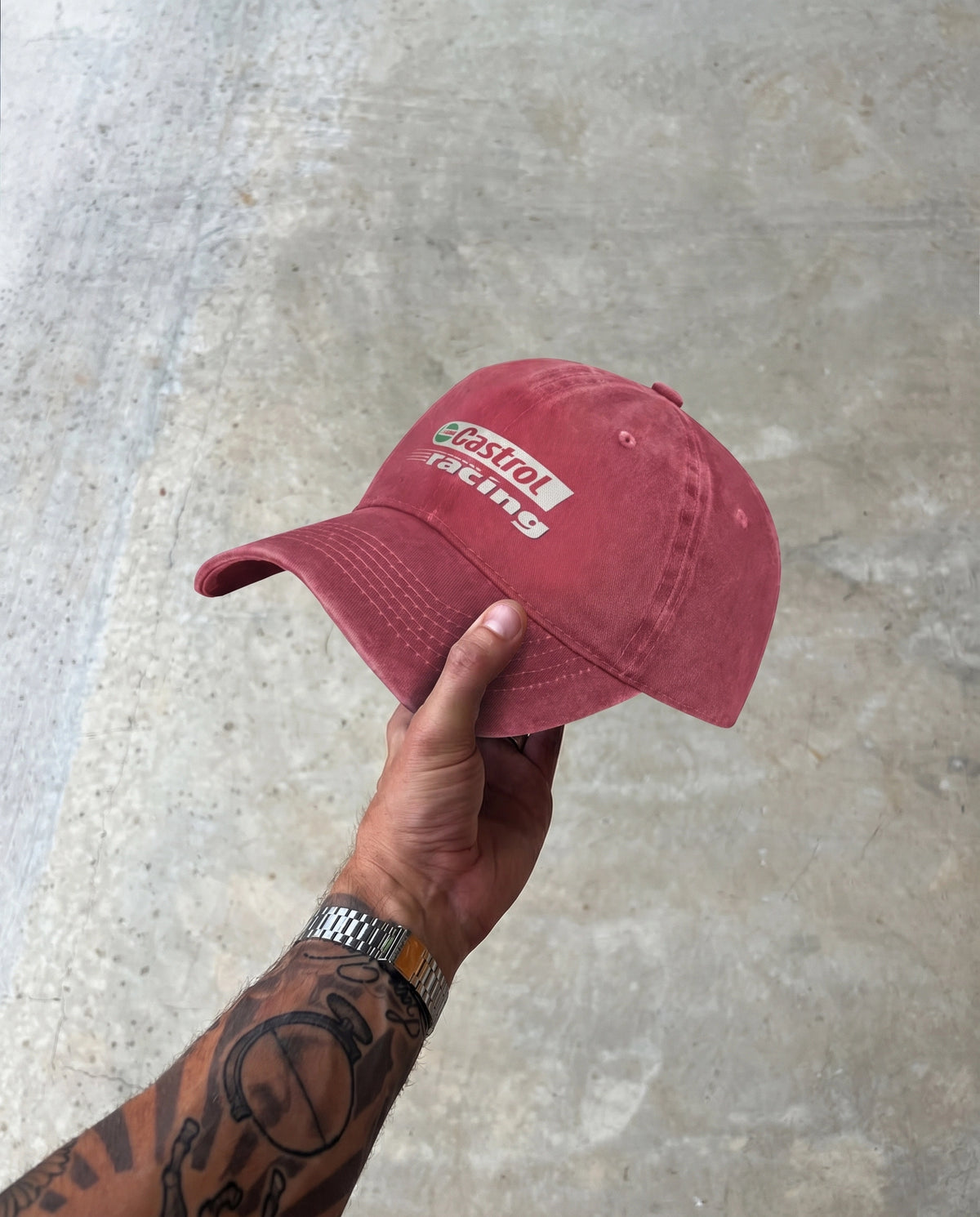 Hand holding the red Castrol Racing dad cap