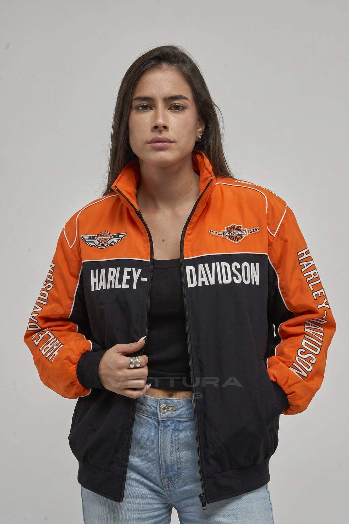 Harley Davidson orange and black jacket on a model, sleeve wordmark detail