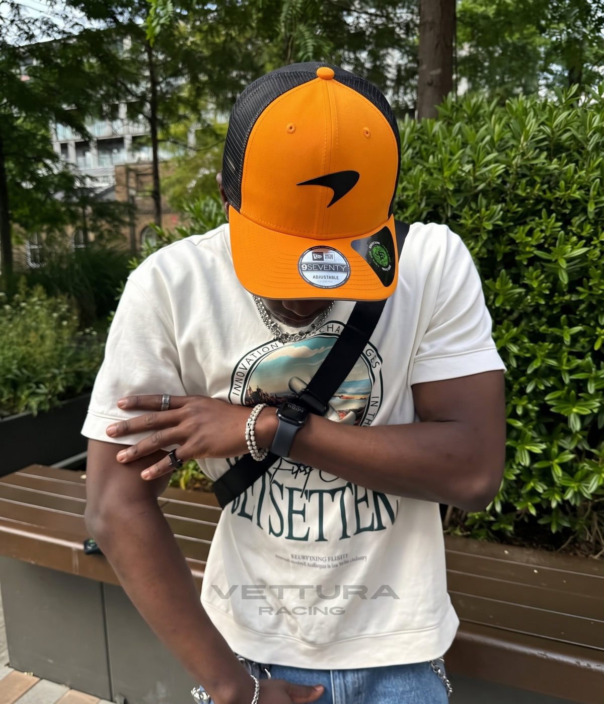 Man wearing the papaya McLaren F1 trucker cap on a park bench