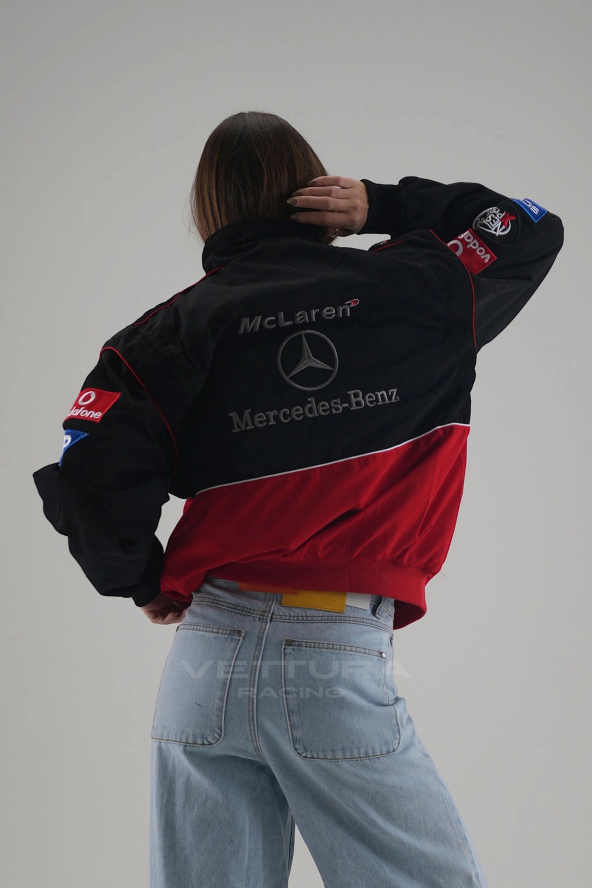 Rear view of the McLaren Mercedes red edition bomber worn with wide jeans