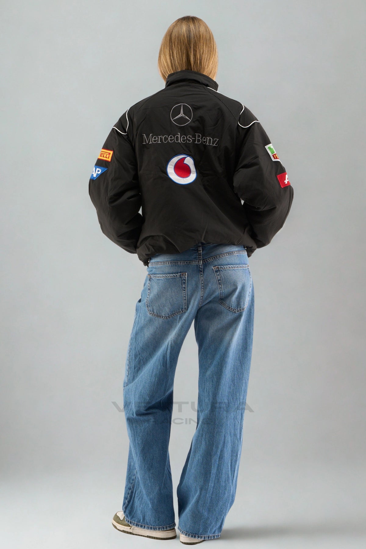 Rear view of the black Mercedes-Benz F1 bomber worn with wide leg jeans