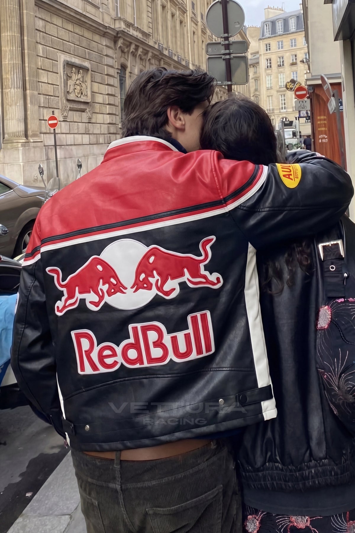 Two people wearing the Red Bull racing leather jacket outdoors
