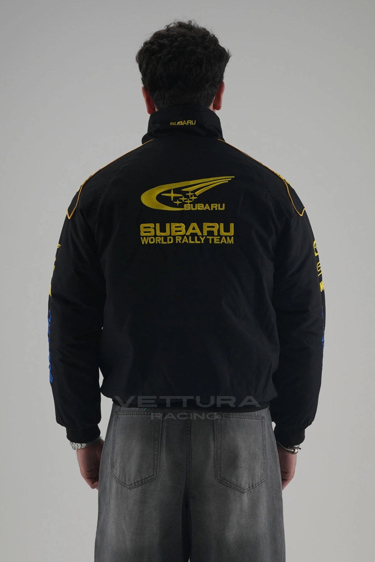 Back of the black Subaru World Rally vintage racing jacket on a model
