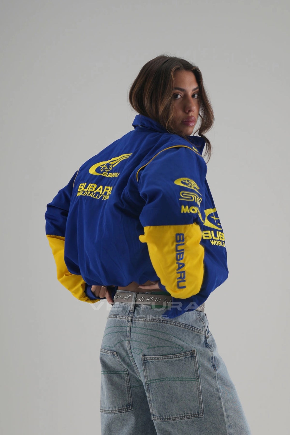 Rear view of the Subaru rally bomber jacket worn with wide leg jeans